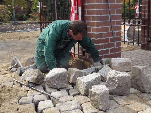 Mitarbeiter beim Verlegen von Steinen Mitarbeiter beim Verlegen von Steinen